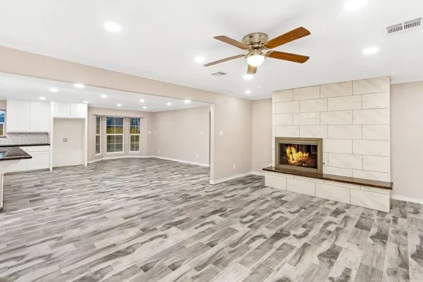 an empty room with a fireplace and ceiling fan