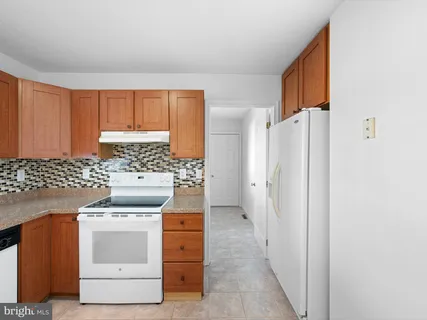 a kitchen with kitchen island granite countertop wooden cabinets and white appliances