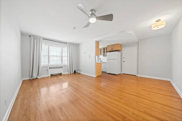 a view of empty room with wooden floor and ceiling fan