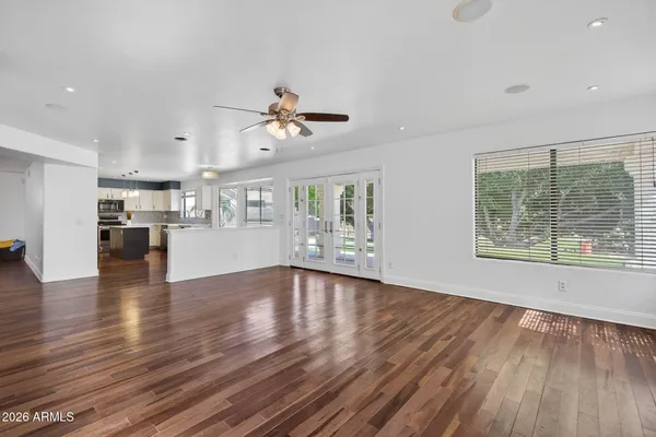 an empty room with windows fireplace and wooden floor