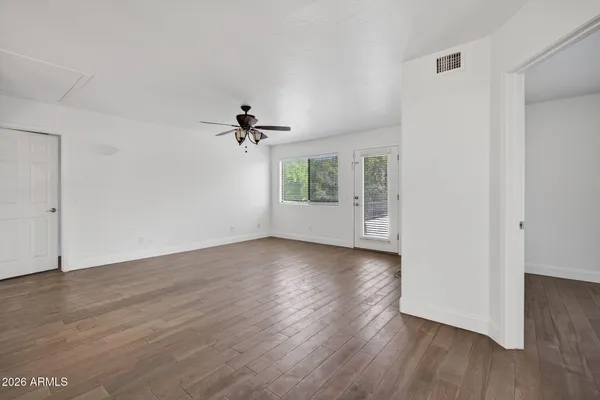 a view of empty room with wooden floor and fan