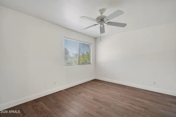 an empty room with wooden floor ceiling fan