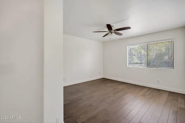 an empty room with wooden floor and ceiling fan
