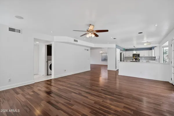 a kitchen with stainless steel appliances kitchen island granite countertop a refrigerator a sink dishwasher a stove and a dining table with wooden floor