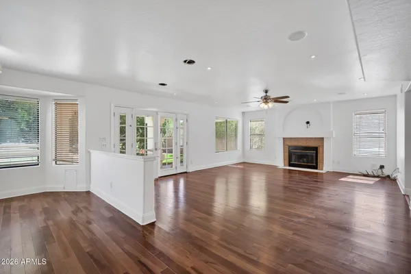 an empty room with wooden floor fireplace and windows