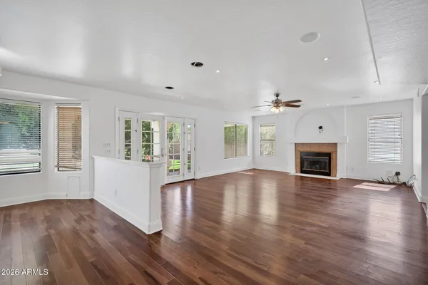 an empty room with wooden floor fireplace and windows
