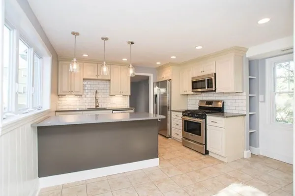 a kitchen with stainless steel appliances granite countertop a stove top oven a sink dishwasher a refrigerator and white cabinets with wooden floor