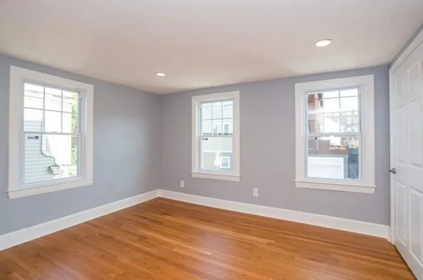 a view of an empty room with wooden floor and window