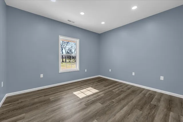 an empty room with wooden floor and natural light