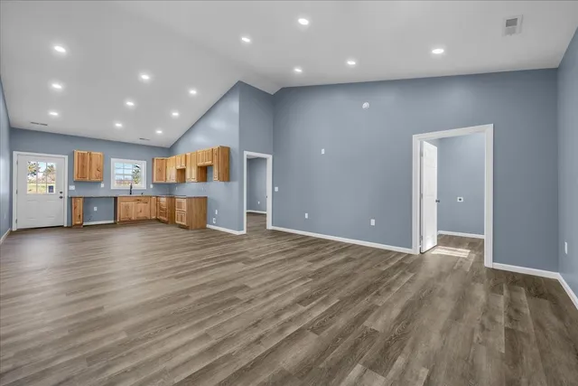 a view of an empty room with wooden floor and windows