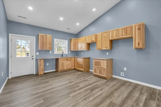 a kitchen with stainless steel appliances granite countertop a sink and cabinets with wooden floor