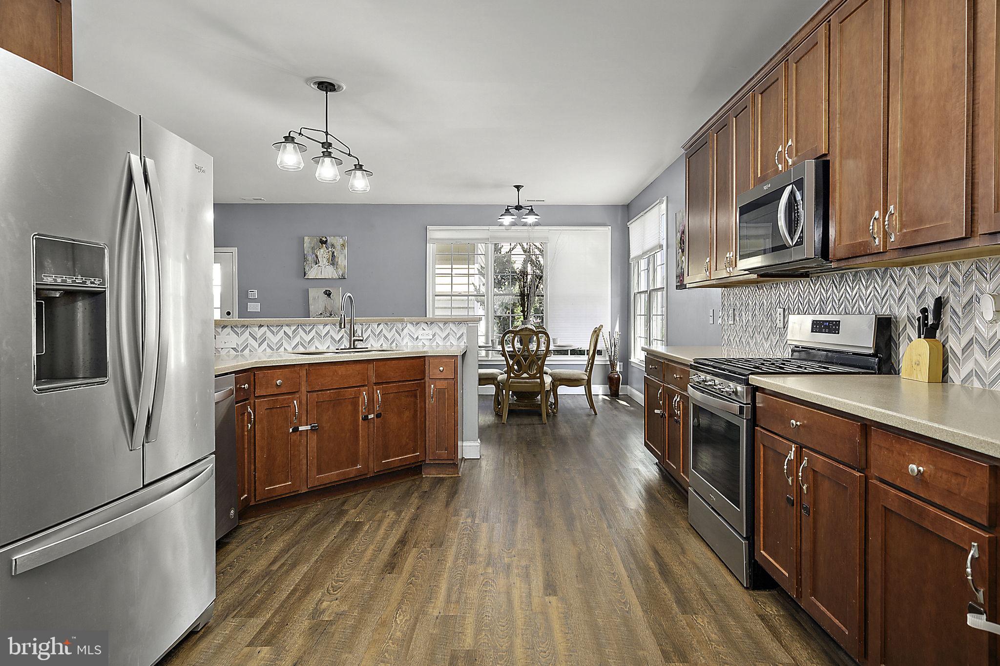 12167 Snug Harbor Road Berlin, MD 21811 - Photo 28 of 107 a kitchen with stainless steel appliances granite countertop a refrigerator a stove top oven a sink dishwasher and wooden cabinets with wooden floor