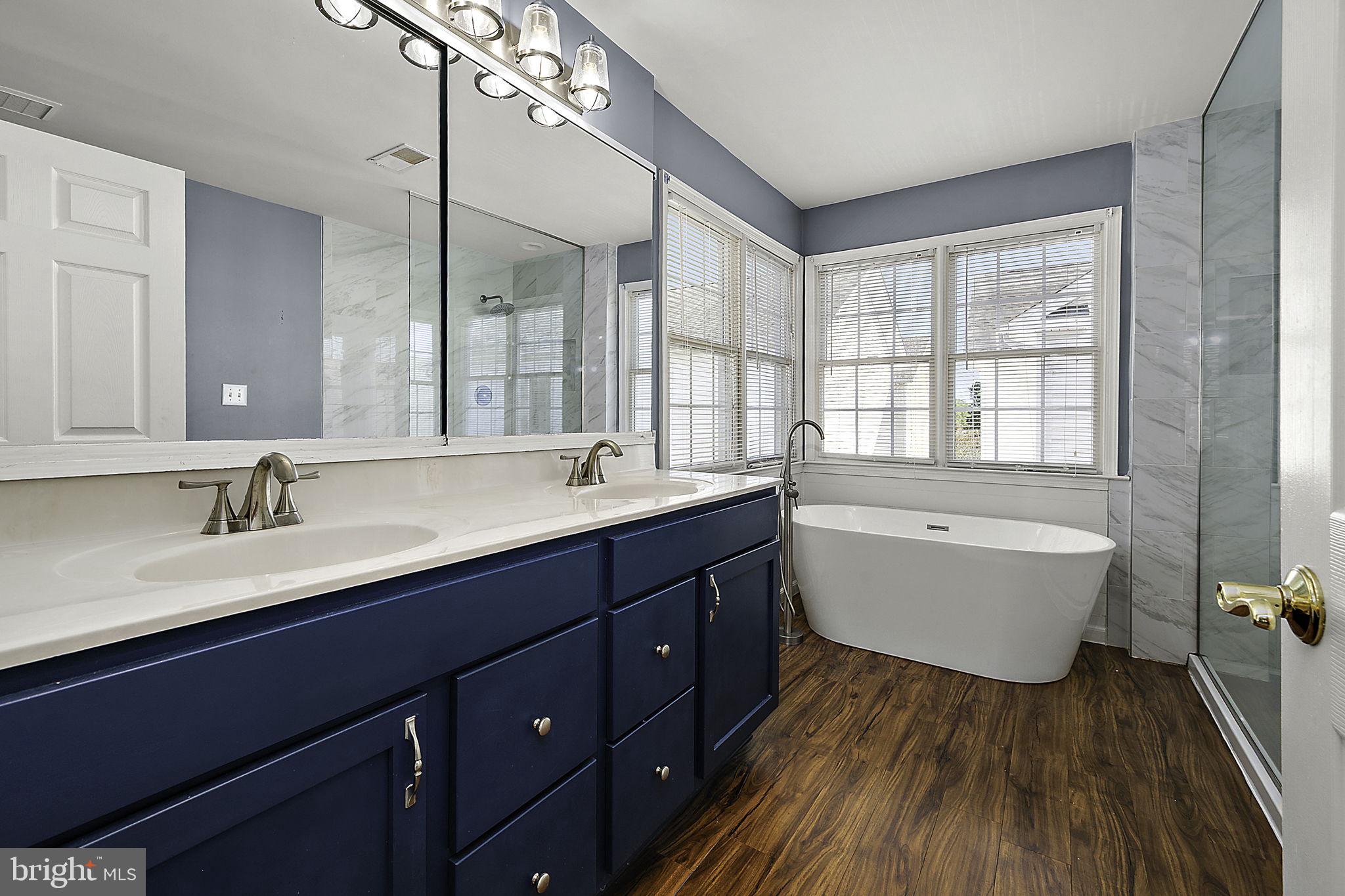 12167 Snug Harbor Road Berlin, MD 21811 - Photo 40 of 107 a bathroom with a double vanity sink a mirror and a bathtub