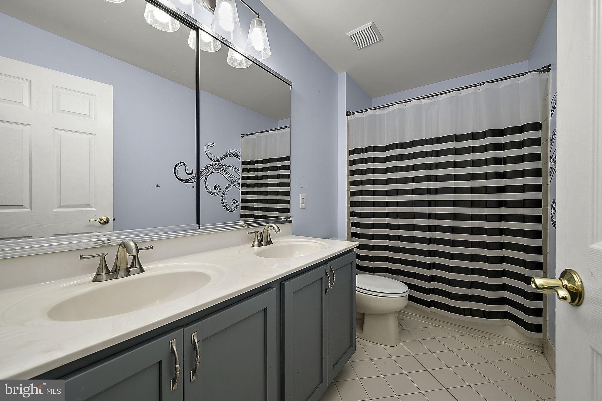 12167 Snug Harbor Road Berlin, MD 21811 - Photo 46 of 107 a bathroom with a double vanity sink toilet and a mirror
