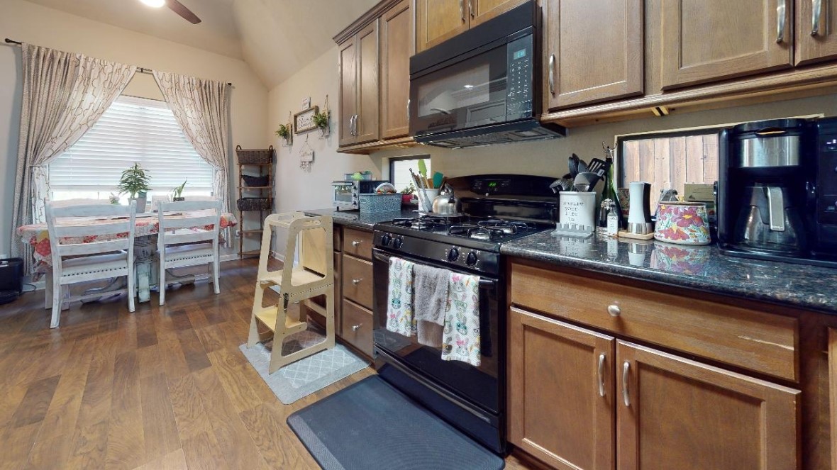 2015 Positano Loop Bryan, TX 77808 - Photo 4 of 15 a kitchen with stainless steel appliances granite countertop a stove a sink dishwasher and microwave with wooden floor