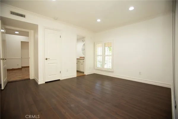 an empty room with wooden floor & windows