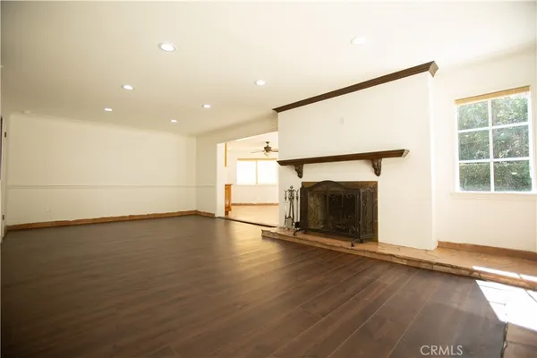 an empty room with wooden floor fireplace and windows