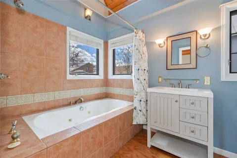 a bathroom with a tub a double vanity sink and a window
