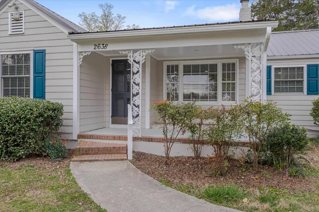 front view of a house with a yard and potted plants