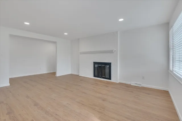 a view of empty room with wooden floor and fireplace