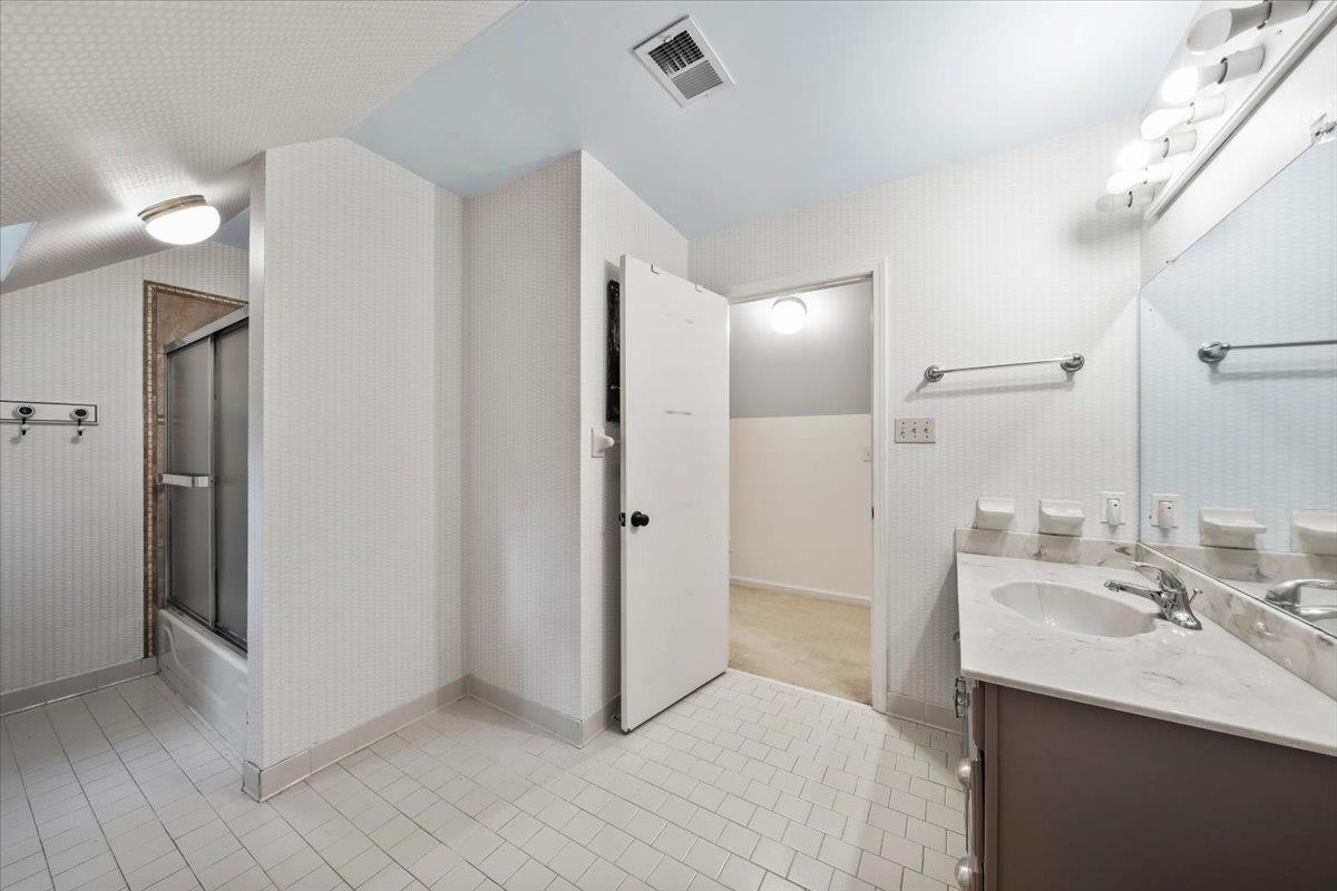 5376 Mason Road Memphis, TN 38120 - Photo 31 of 37 Bathroom featuring vaulted ceiling, vanity, tile patterned flooring, and bath / shower combo with glass door