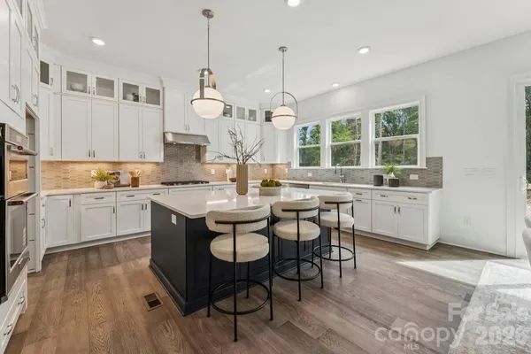 a kitchen with a sink stove cabinets and wooden floor