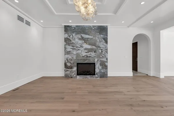 a view of an empty room with a fireplace and a chandelier fan