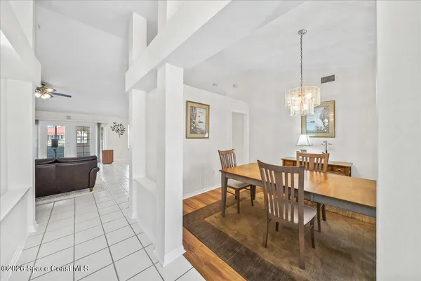 a view of a dining room and livingroom with furniture wooden floor a rug a fireplace and a chandelier