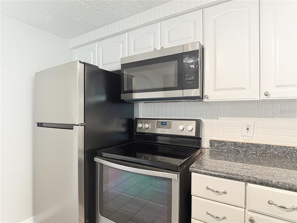 7827 Butler Avenue Hudson, FL 34667 - Photo 13 of 82 a kitchen with stainless steel appliances granite countertop a stove a microwave and a refrigerator