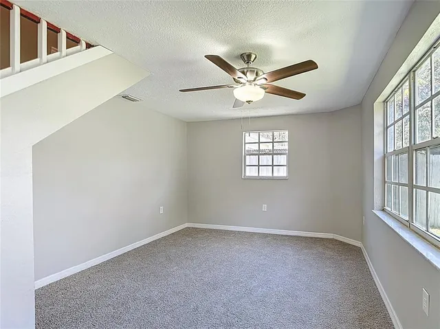 an empty room with windows and fan
