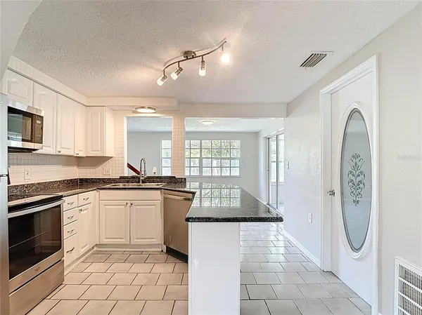 a kitchen with granite countertop white cabinets and appliances