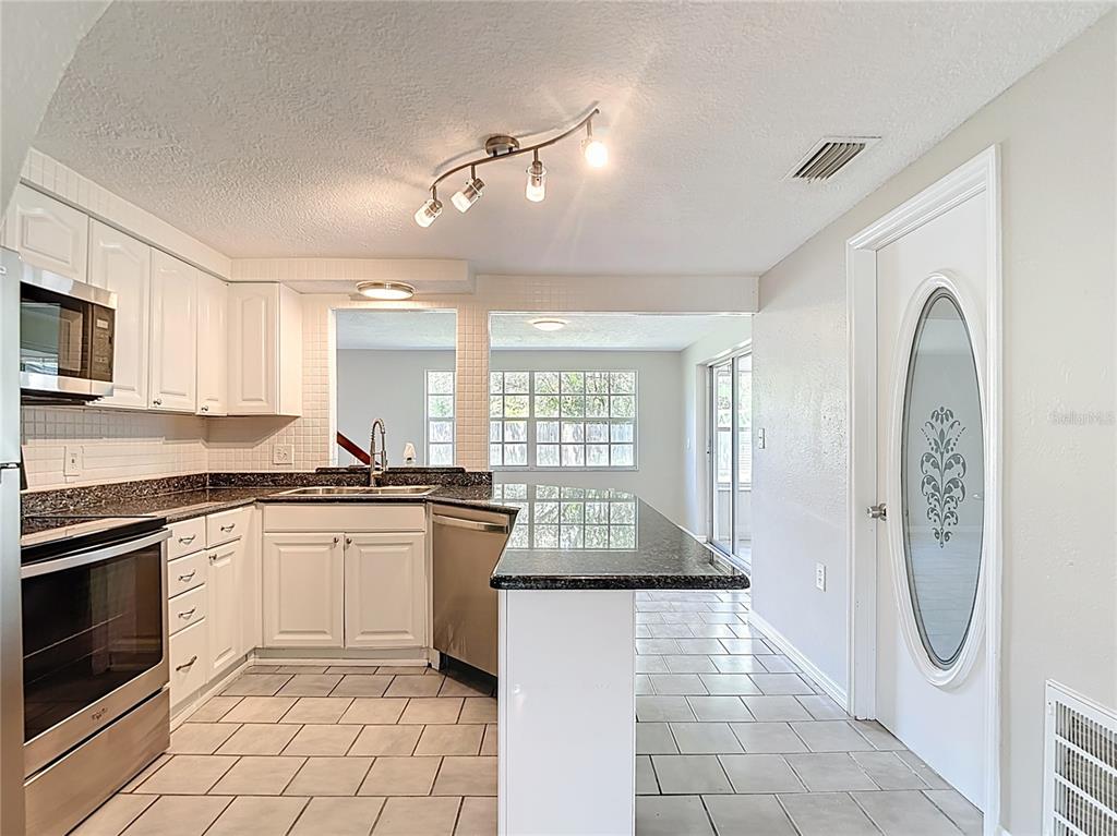 7827 Butler Avenue Hudson, FL 34667 - Photo 8 of 82 a kitchen with granite countertop a stove a sink and a refrigerator
