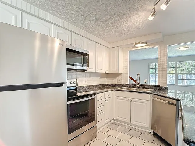 a kitchen with granite countertop a refrigerator sink and stove