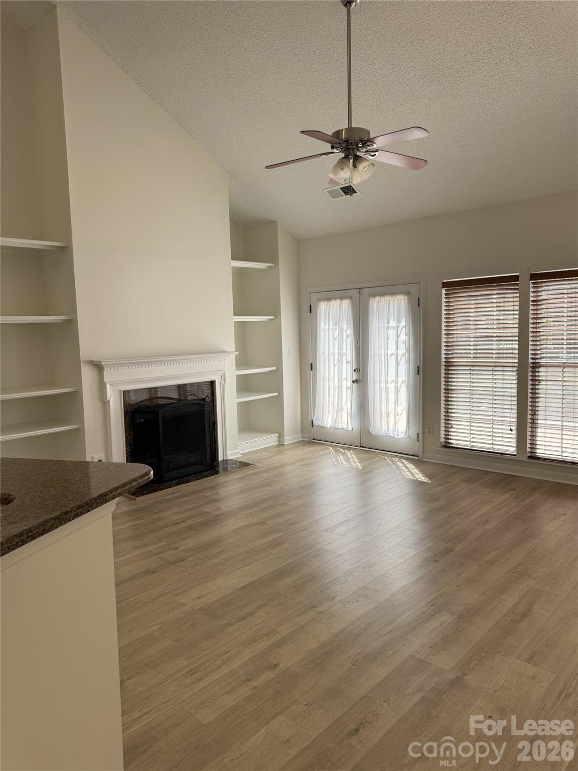 11408 Coreopsis Road Charlotte, NC 28213 - Photo 11 of 38 an empty room with wooden floor fireplace and windows