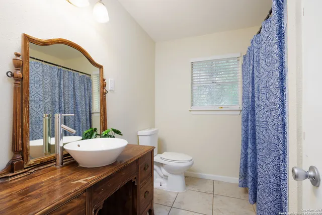 a bathroom with a granite countertop sink mirror vanity and a toilet