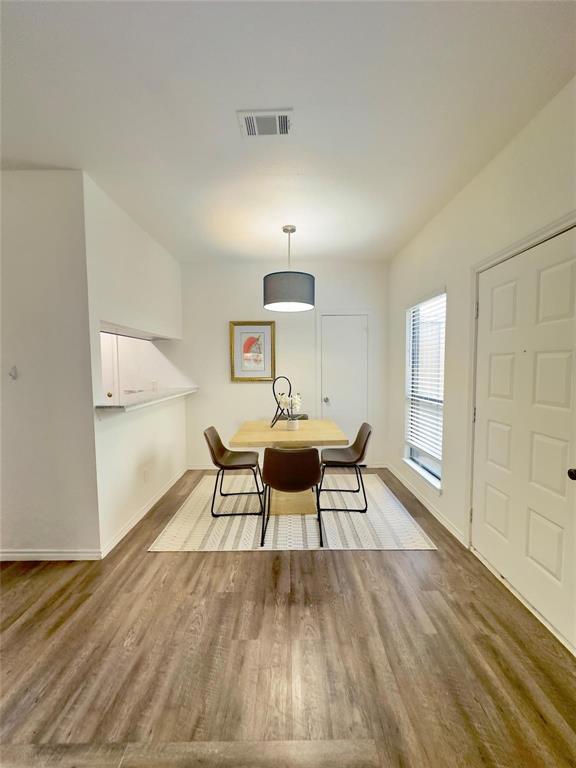 7340 Skillman Street, Unit 405 Dallas, TX 75231 - Photo 4 of 18 Dining area featuring wood-finish flooring, a contemporary pendant light fixture, and a window with blinds