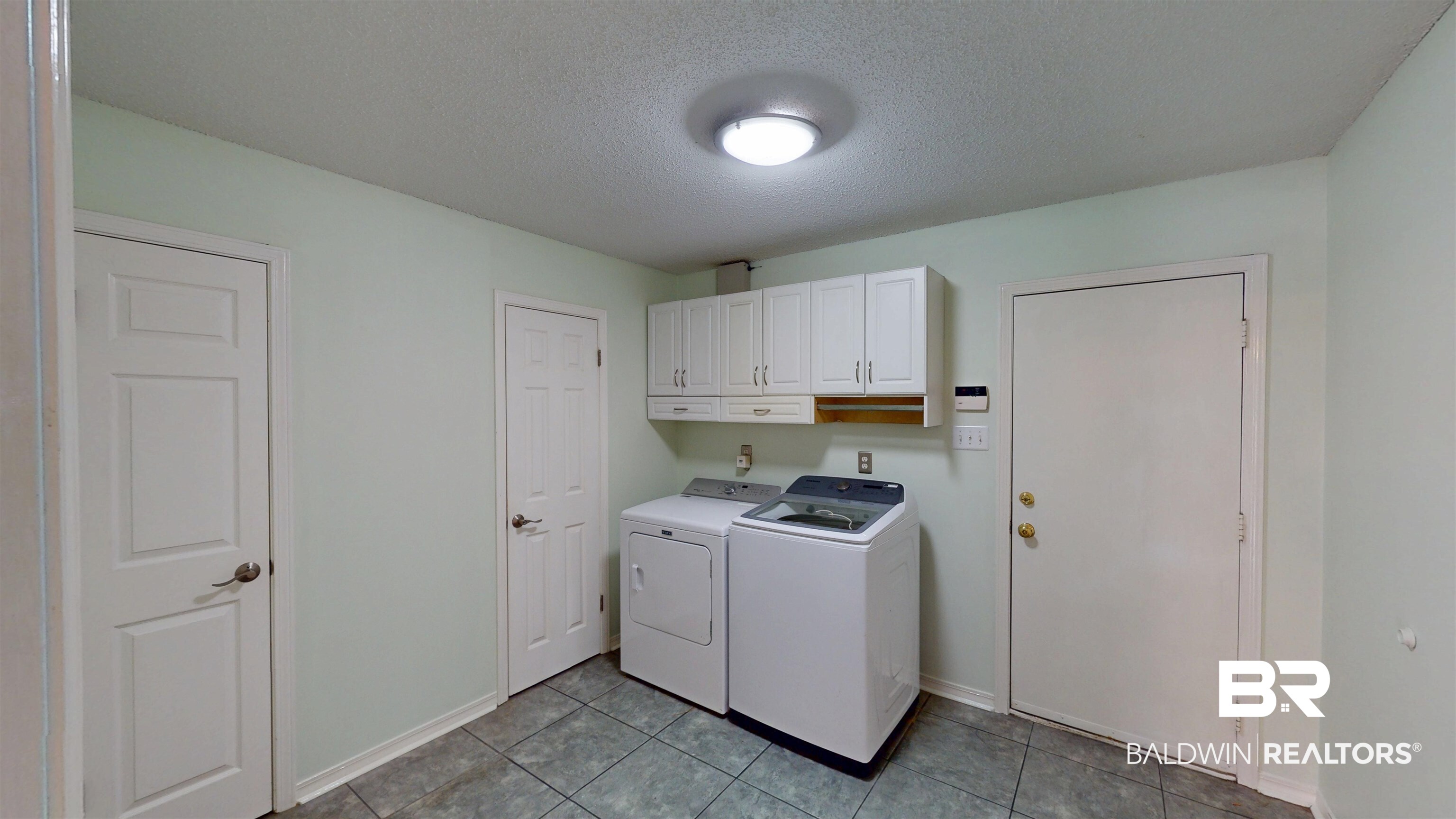 7310 Cheryl Court Mobile, AL 36695 - Photo 21 of 23 Large laundry room featuring a textured ceiling, cabinet space, washer and dryer, and light tile patterned floors