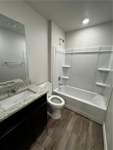 a bathroom with a granite countertop sink a toilet a mirror and bathtub