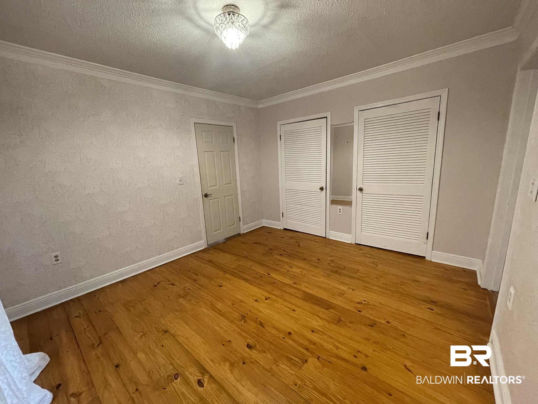 6621 Purvis Road Daphne, AL 36527 - Photo 24 of 59 Unfurnished bedroom featuring two closets, light wood-style floors, a textured ceiling, and crown molding