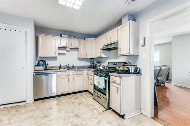 a kitchen with stainless steel appliances granite countertop a refrigerator sink and white cabinets