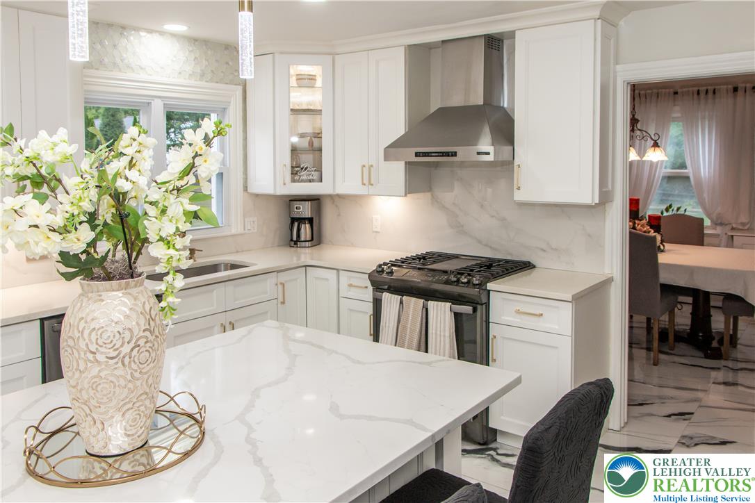 3582 Country Club Road Easton, PA 18045 - Photo 5 of 48 White cabinetry and elegant quartz countertops define this immaculate kitchen, featuring a gas range and built-in range hood.