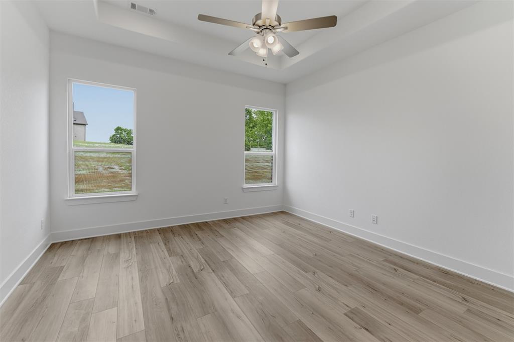 906 Perrin Lane Van Alstyne, TX 75495 - Photo 20 of 30 an empty room with wooden floor chandelier fan and windows
