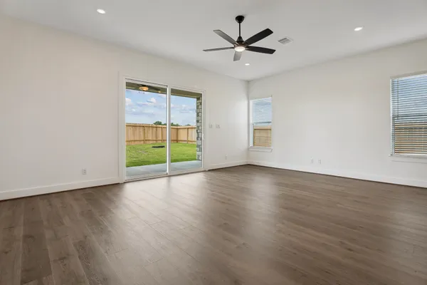 a view of an empty room with a window and wooden floor
