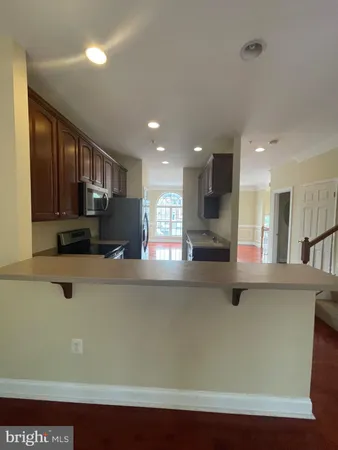 a kitchen with stainless steel appliances granite countertop a refrigerator a sink a stove and a refrigerator with wooden floor