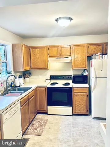 a kitchen with stainless steel appliances granite countertop a refrigerator a sink dishwasher a stove with white cabinets and wooden floor