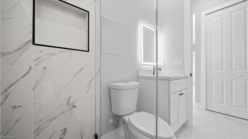 926 Winters Street East Lehigh Acres, FL 33974 - Photo 13 of 36 a bathroom with a toilet a sink and mirror