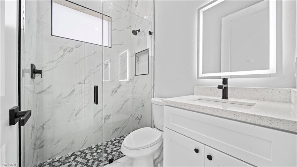 926 Winters Street East Lehigh Acres, FL 33974 - Photo 18 of 36 a bathroom with a granite countertop toilet sink and a mirror