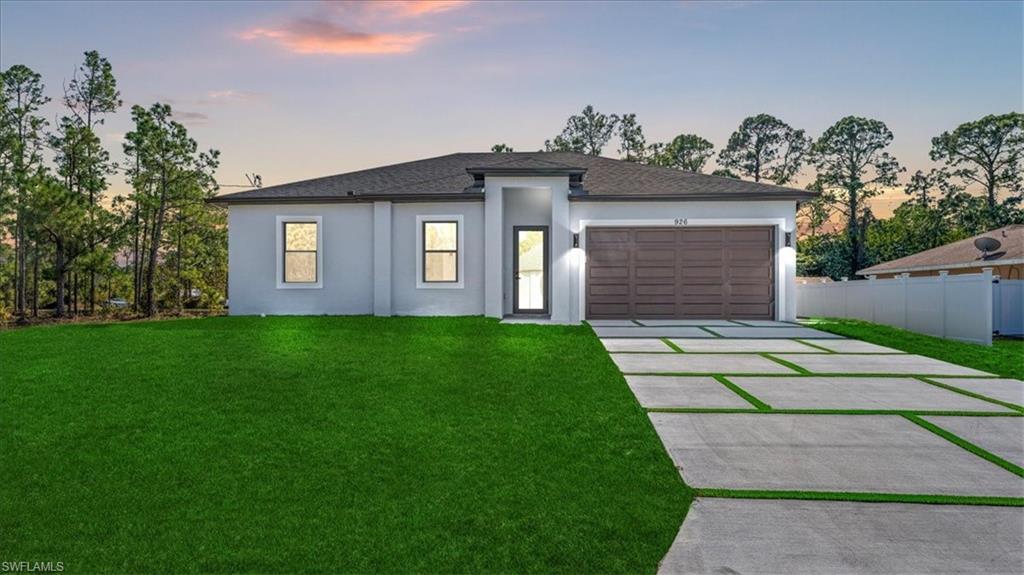 926 Winters Street East Lehigh Acres, FL 33974 - Photo 2 of 36 a front view of a house with a garden and plants