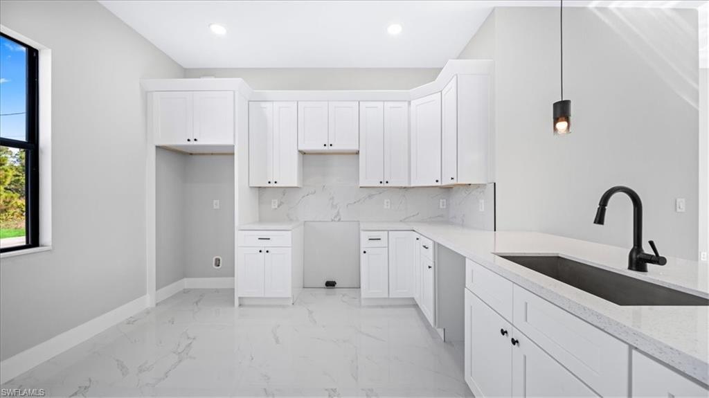 926 Winters Street East Lehigh Acres, FL 33974 - Photo 31 of 36 a kitchen with white cabinets and a sink