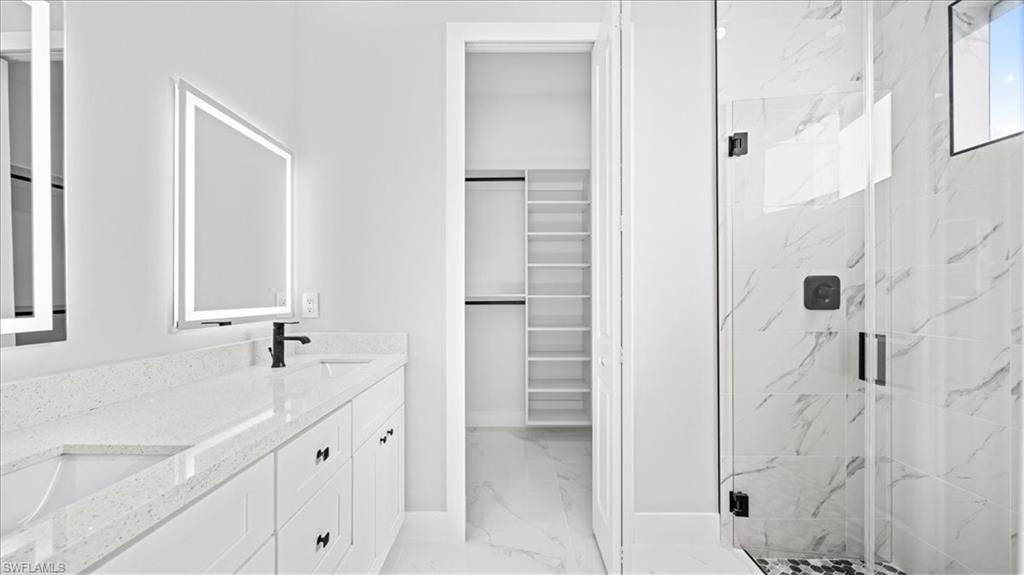 926 Winters Street East Lehigh Acres, FL 33974 - Photo 10 of 36 a bathroom with a double vanity sink a mirror and a shower